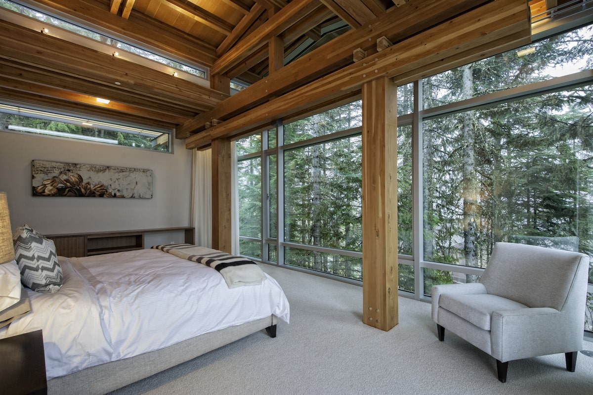Interior d’un dormitori en una casa de camp amb finestres panoràmiques