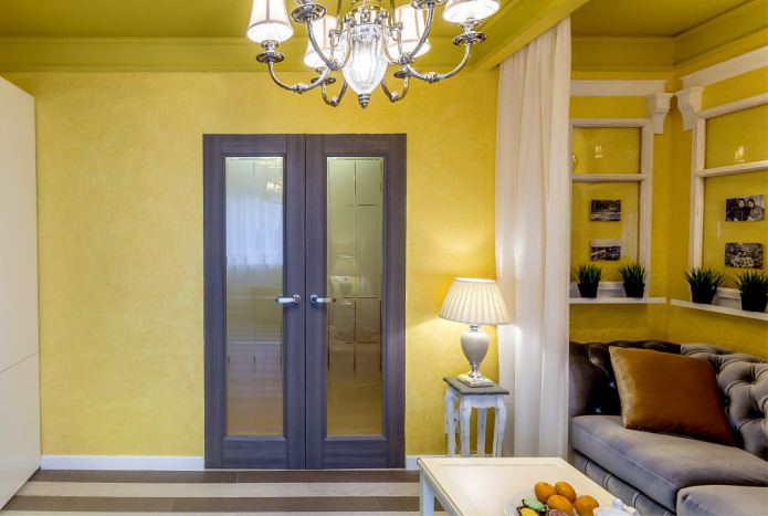 połączenie żółtych ścian z ciemnobrązowymi drzwiami ze szklanymi wstawkami