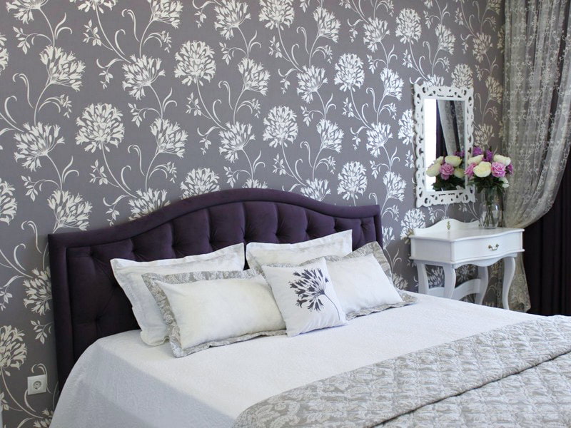 Biele kvetinové vzory na sivých tapetách v spálni