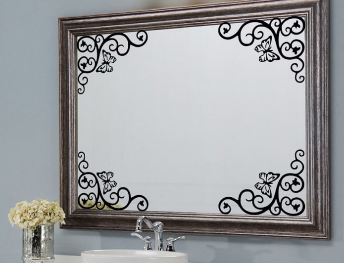 spogulis ar uzlīmēm vannas istabas interjerā