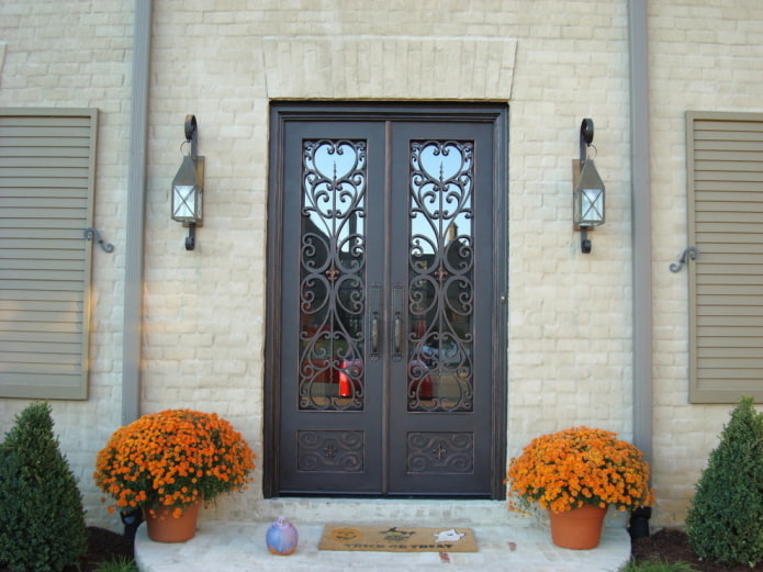 veranda vidieckeho domu so vstupnými dverami s tepaným železom a sklom