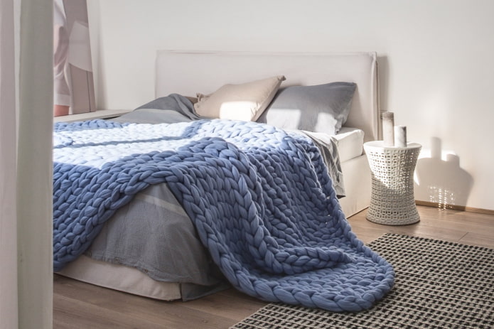 lit avec couvre-lit en grosse maille dans la chambre