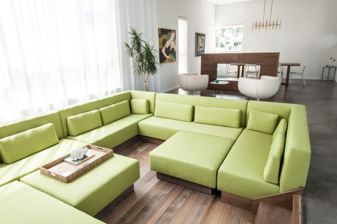 interjerā zaļš modulārais dīvāns
