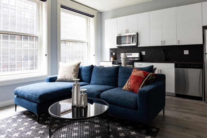 dīvāna modelis ar zilu otomanu interjerā