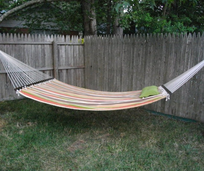 een brede hangmat bevestigd aan een houten hek