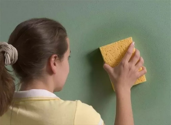 שוטף את הקיר עם ספוג