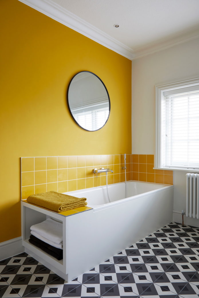 חדר אמבטיה עם קיר צהוב ורצפת פסיפס בשחור לבן