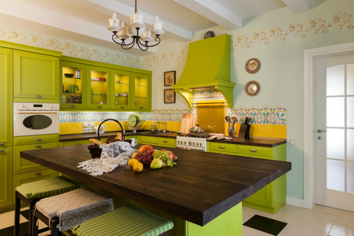 virtuve ar gaiši zaļu mēbeļu komplektu un dzeltenu priekšautu