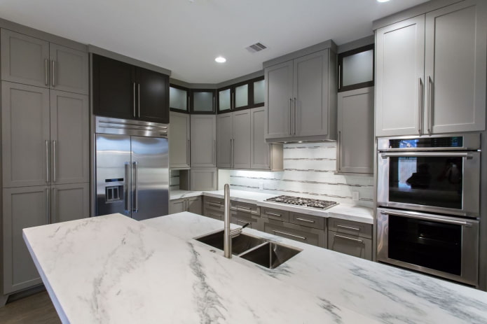 virtuvė su šviesiai pilkais baldais ir balto akmens stalviršiais