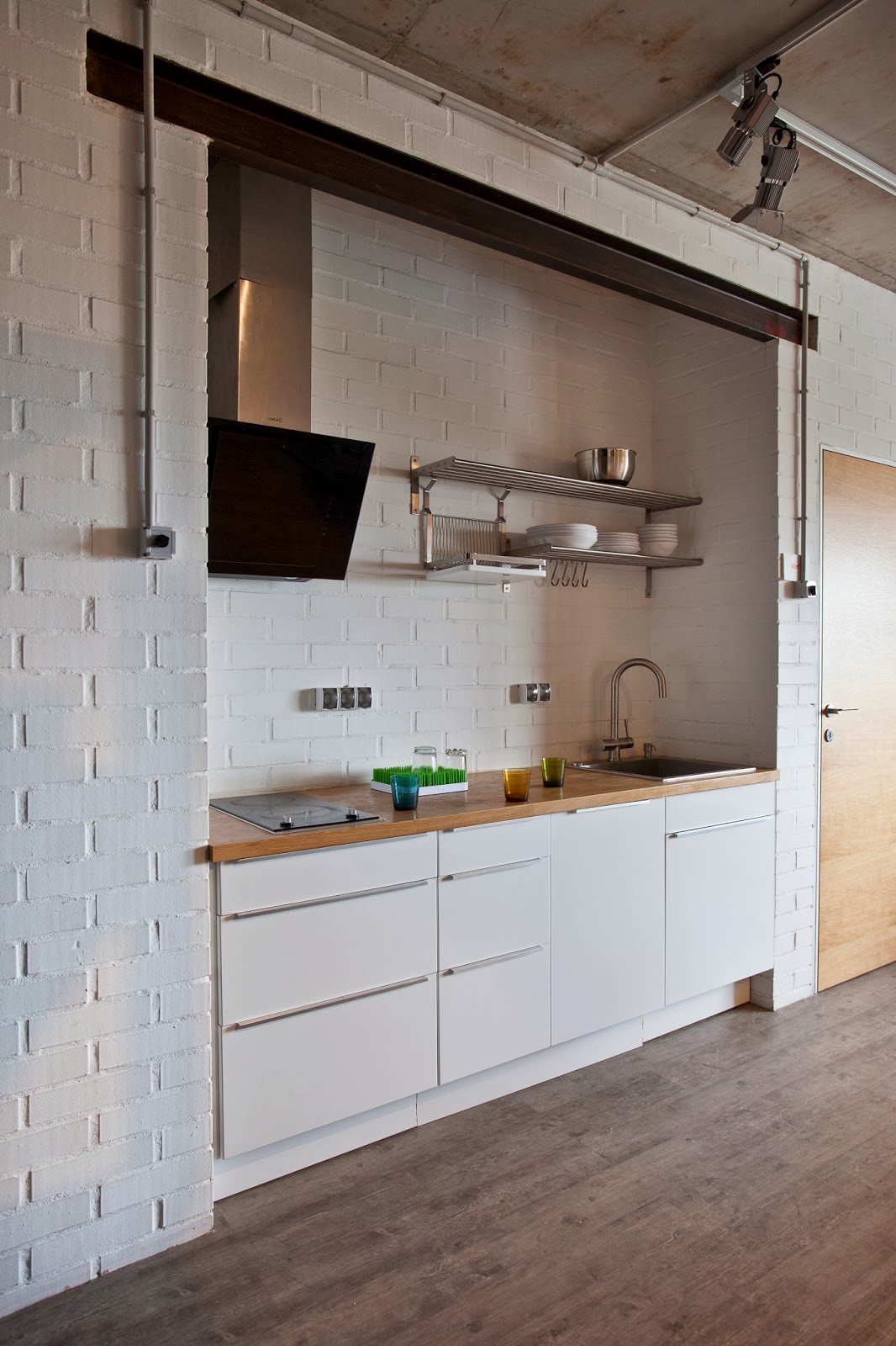 κουζίνα με λευκούς τοίχους από τούβλα στο εσωτερικό ενός δημιουργικού διαμερίσματος